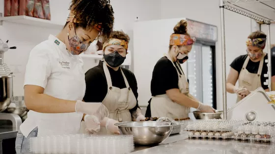 A chef working with her team in a busy shop